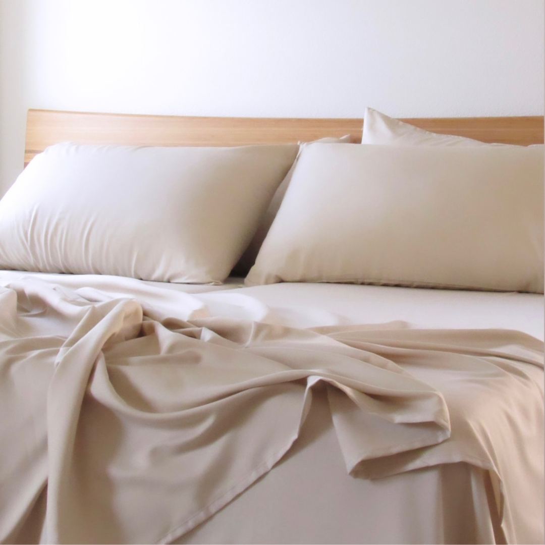 A beige copper-infused bamboo sheet set on a bed