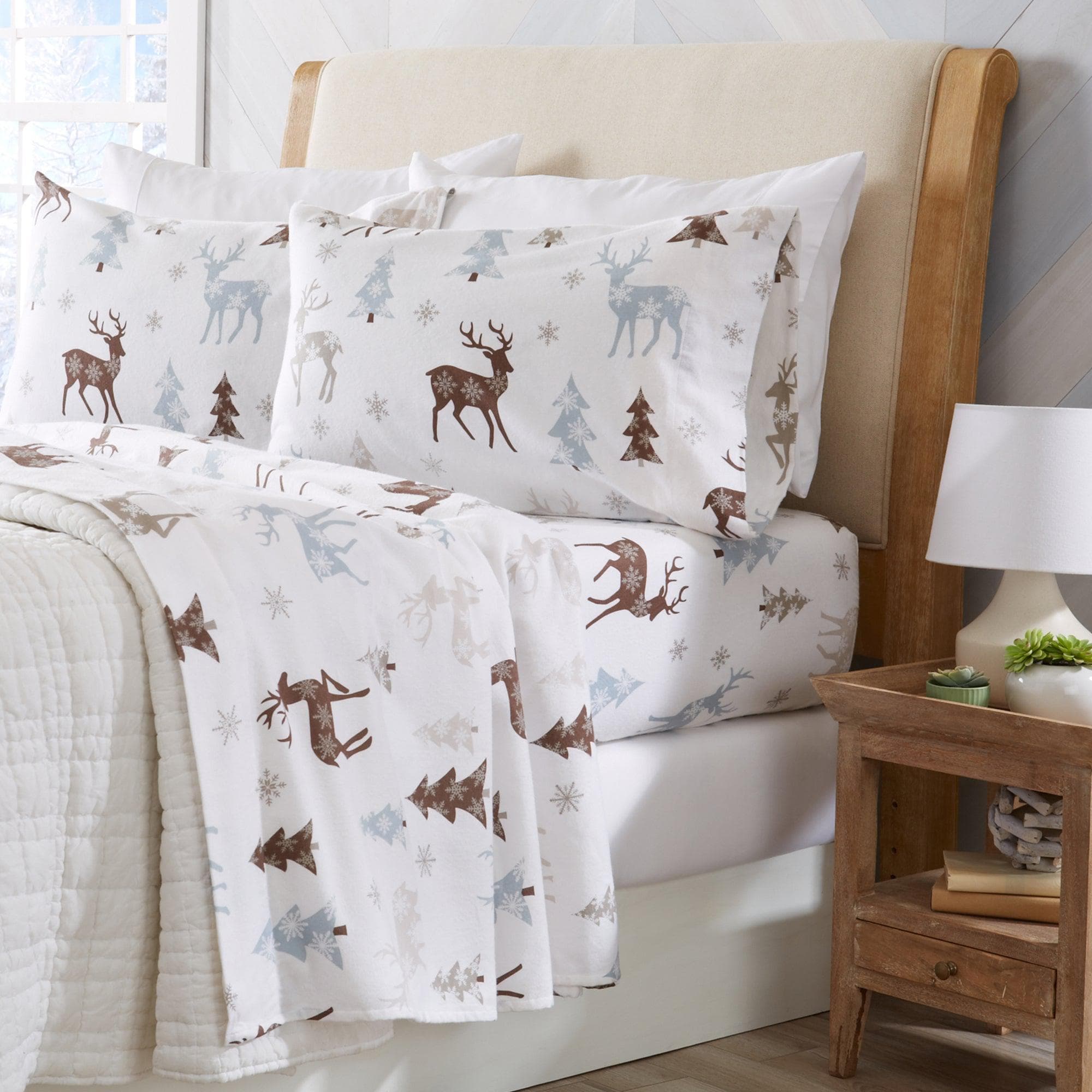 Bed with deer and tree patterned bedding in a bedroom setting.