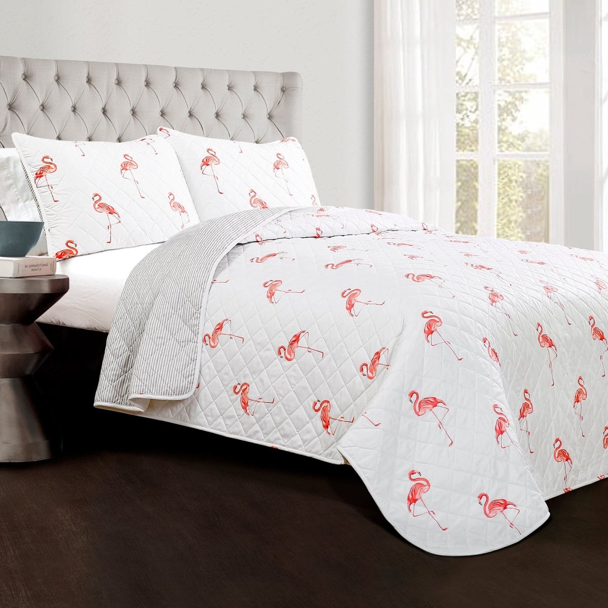 Flamingo-patterned quilt set on a bed with a gray headboard.