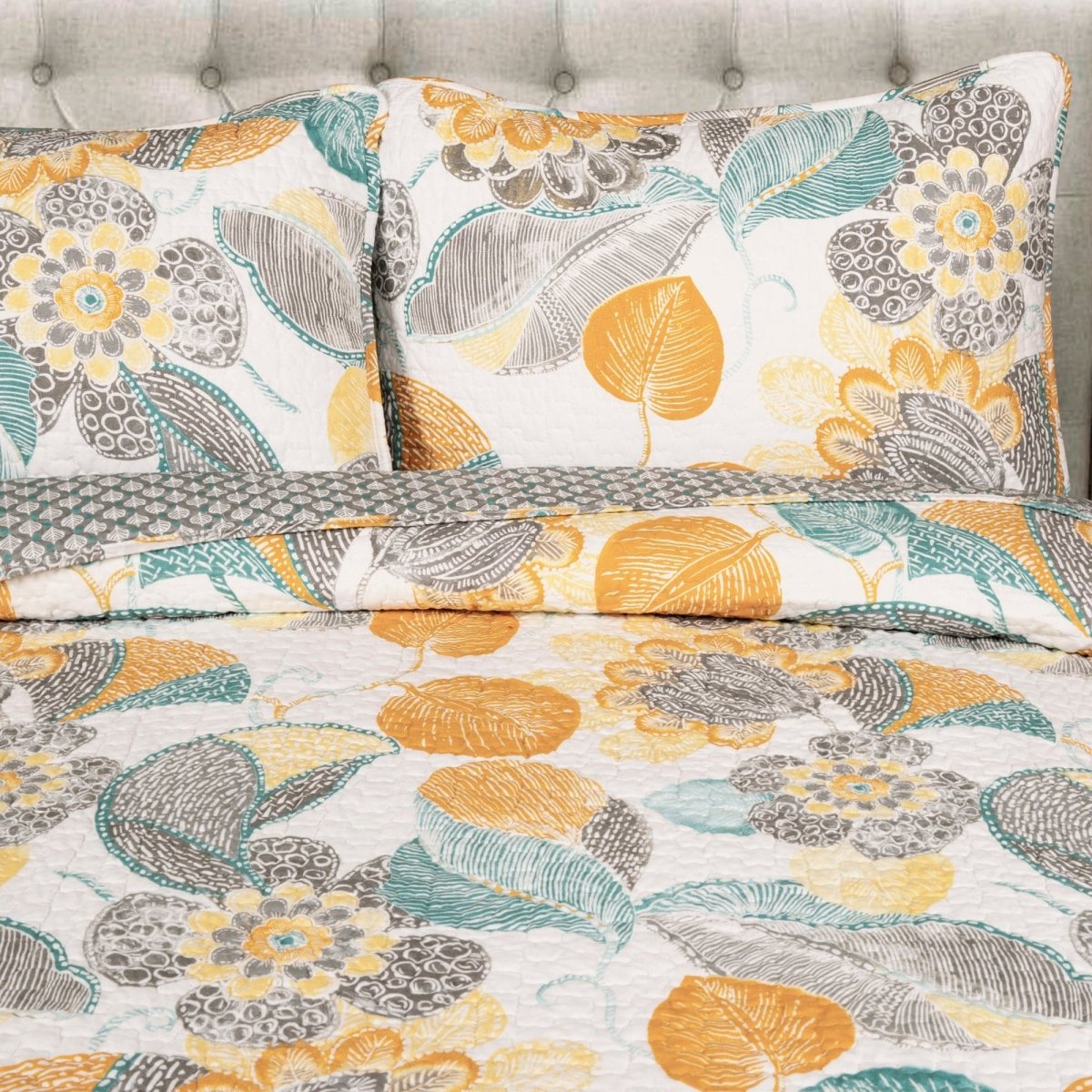 Floral patterned bedding set with yellow, gray, and blue colors on a bed.
