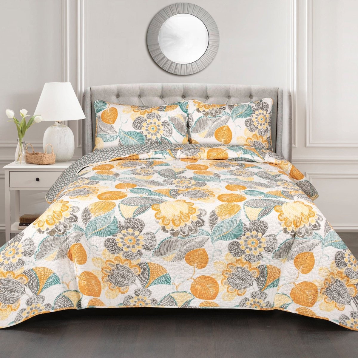 Floral patterned comforter set on a bed in a bedroom setting with a lamp and mirror.