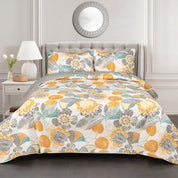 Floral patterned comforter set on a bed in a bedroom setting with a lamp and mirror.
