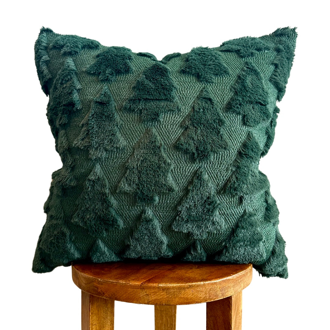 A dark green textured throw pillow with a raised tree pattern, displayed on a wooden stool against a white background.