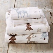 Stack of folded fabric with winter-themed patterns on a wooden surface