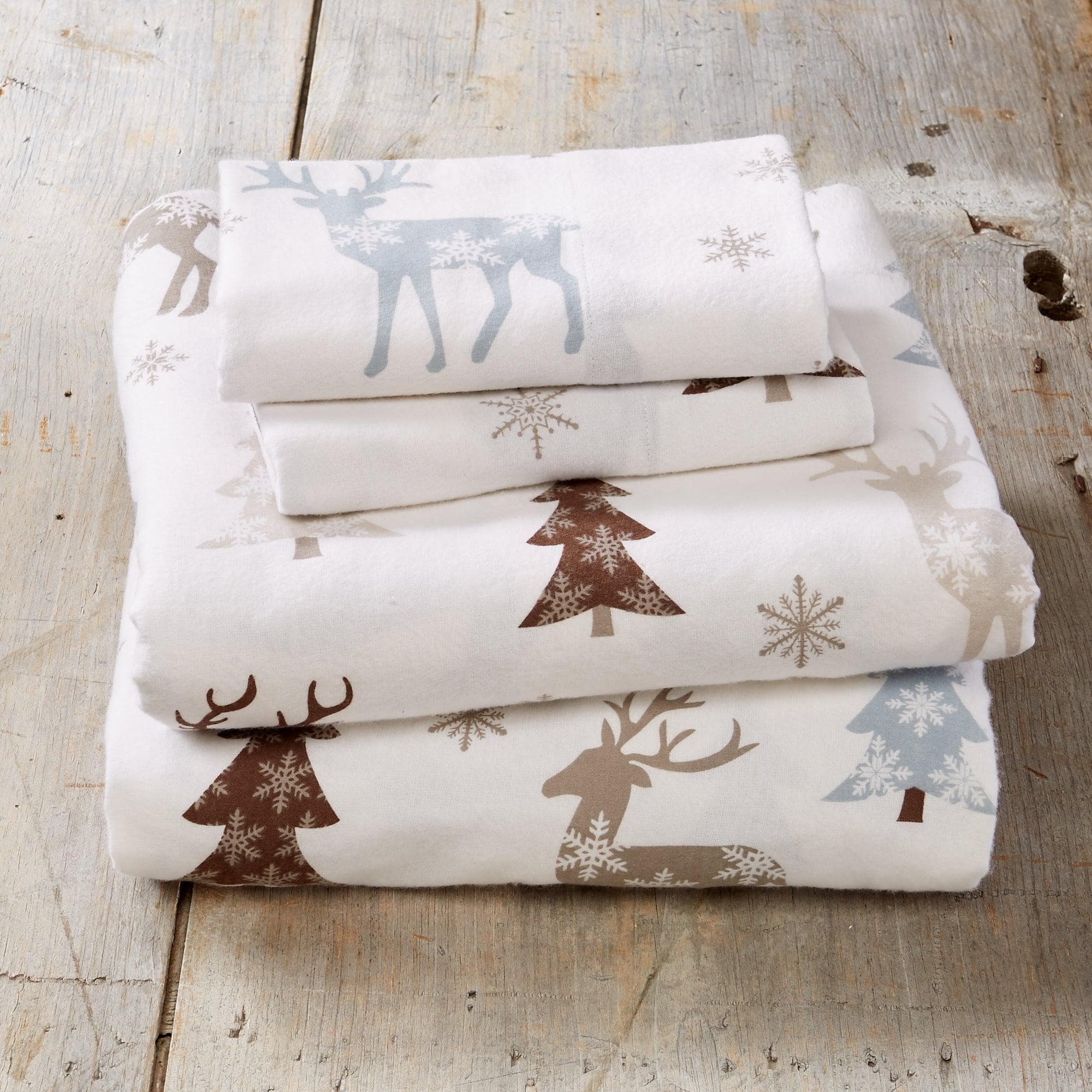 Stack of folded fabric with winter-themed patterns on a wooden surface