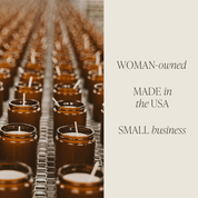 Row of small candles in glass jars on a metal rack with text 'WOMAN-owned, MADE in the USA, SMALL business' on a beige background.