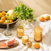 Decorative setting with candles, fruits, and flowers on a light surface.