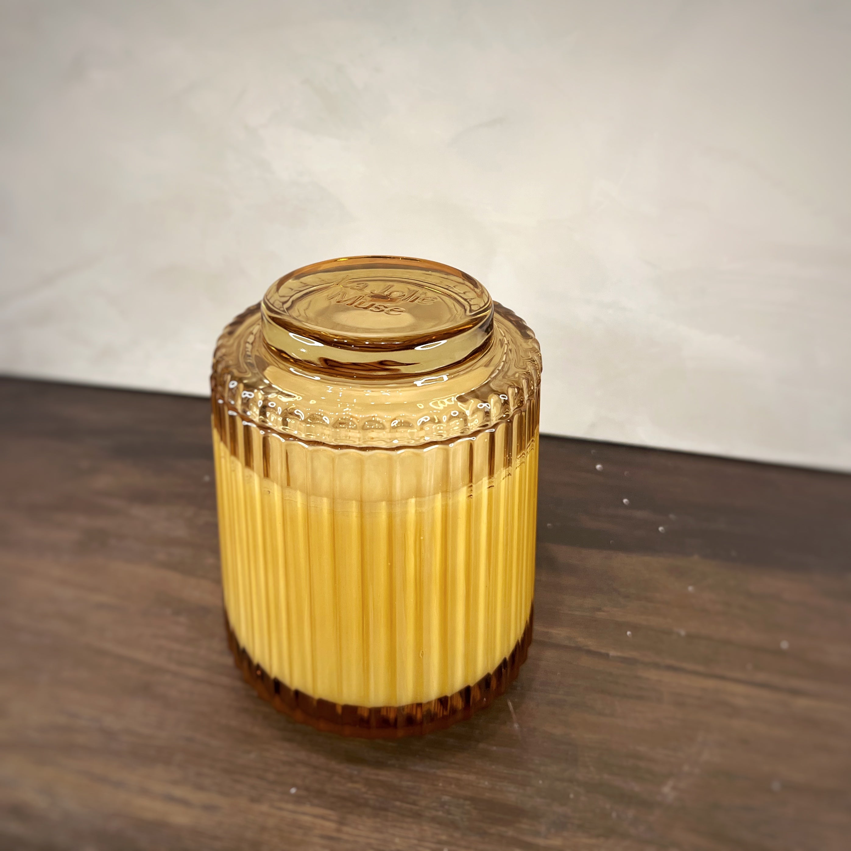 Gold-colored cylindrical container with a lid on a wooden surface