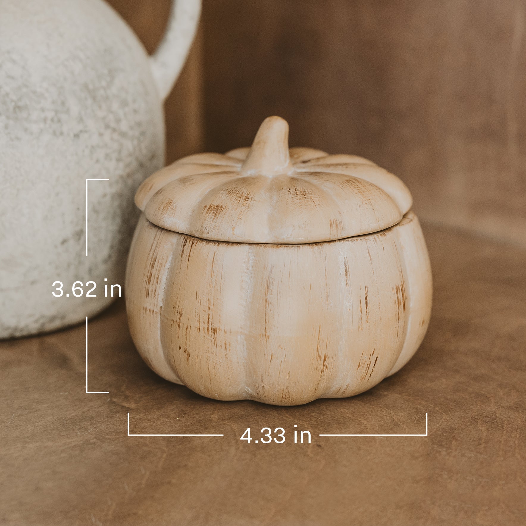 Decorative pumpkin-shaped container with dimensions on a brown surface