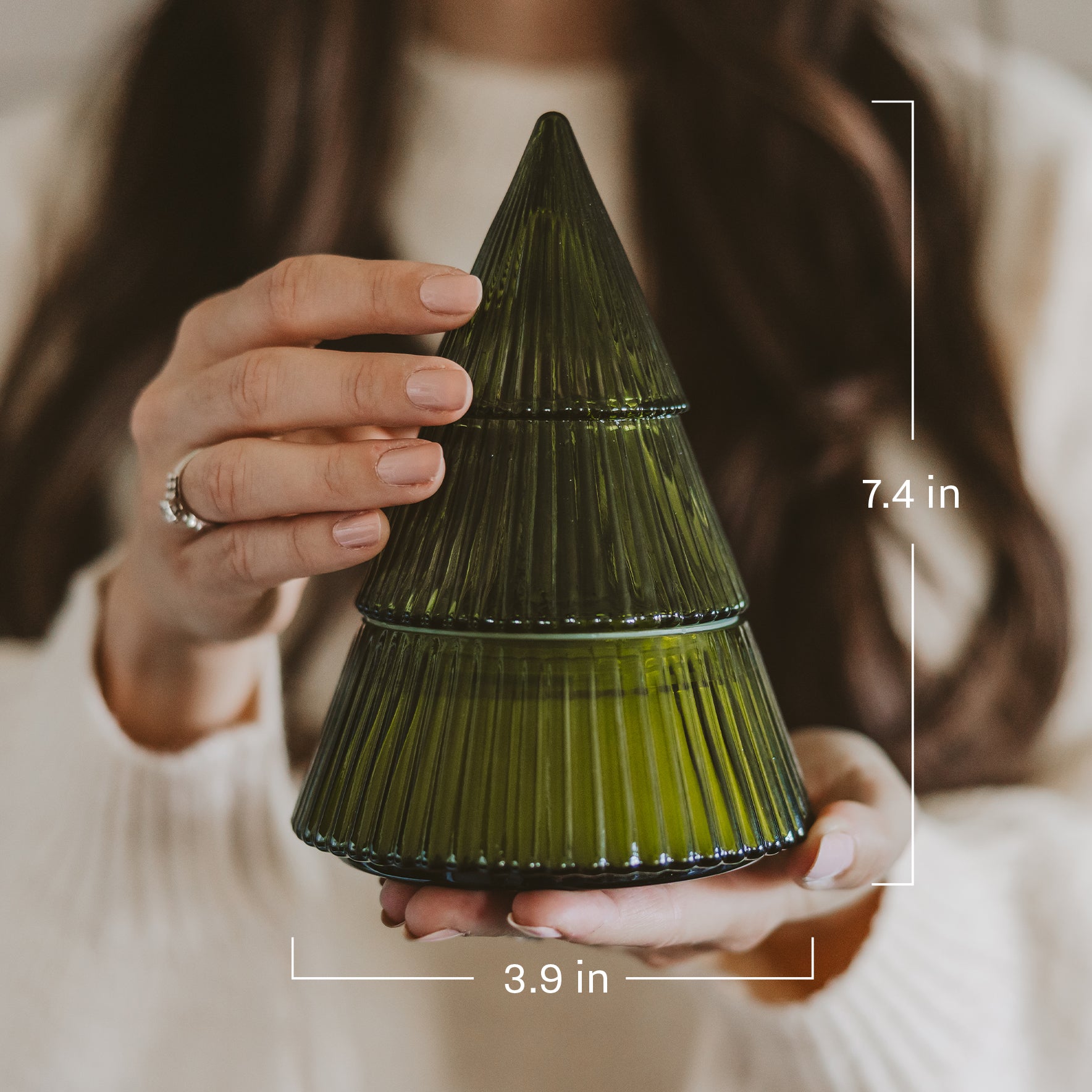 A person holds a small ribbed glass Christmas tree-shaped container in olive green. White measurement lines and text indicate dimensions of 7.