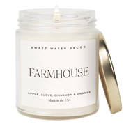 Candle in a jar labeled 'Farmhouse' by Sweet Water Decor on a green background