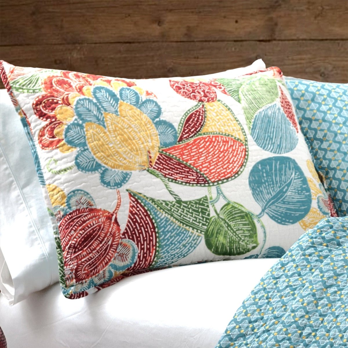 Colorful floral-patterned pillow on a bed with a wooden headboard.