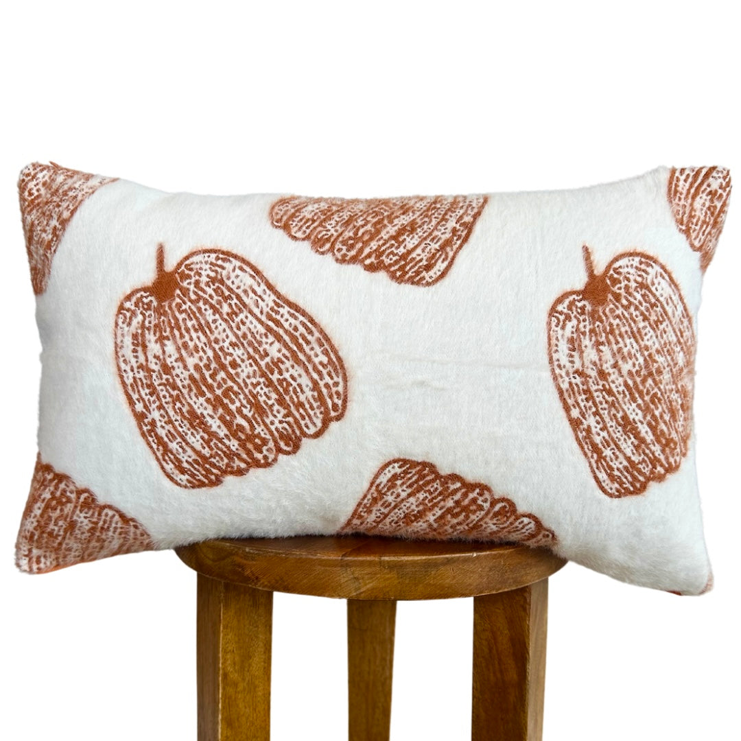 Decorative pillow with brown pumpkin pattern on a white background, placed on a wooden stool.