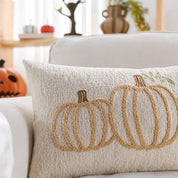 Decorative pillow with pumpkin design on a couch in a cozy living room.