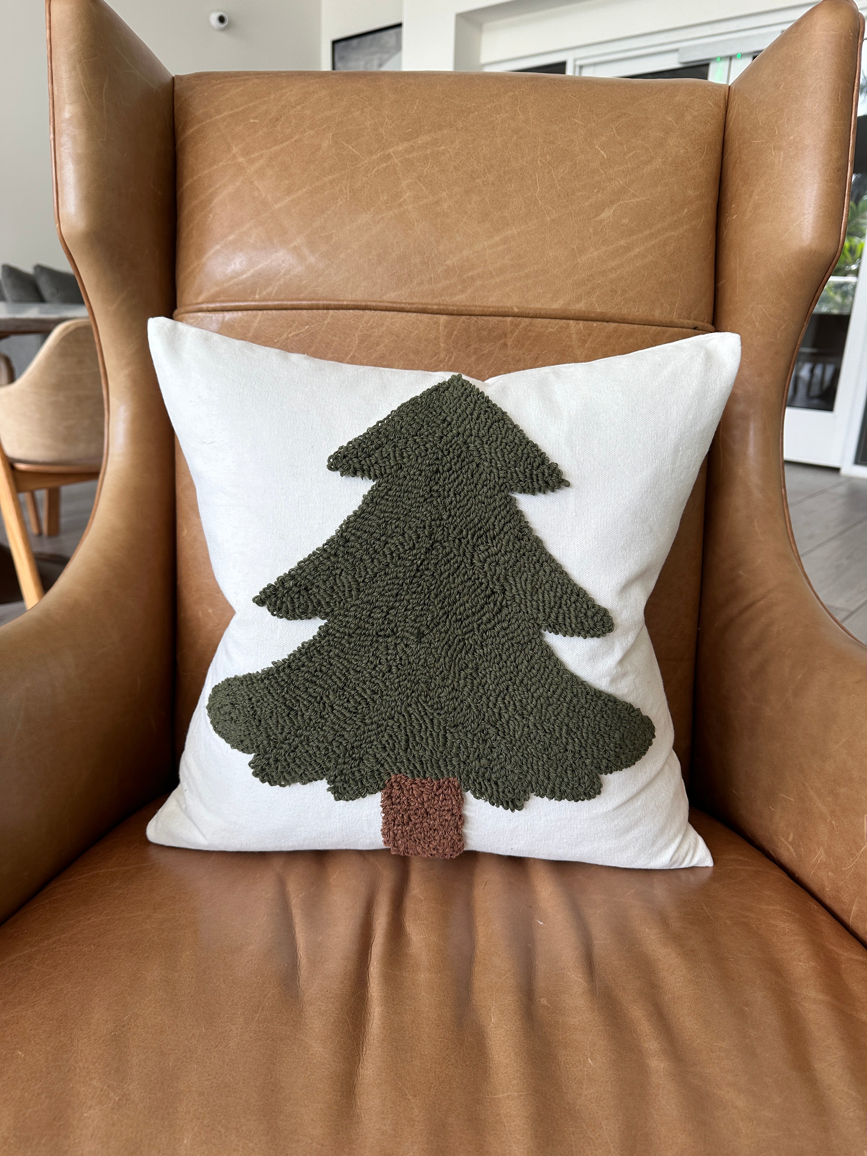 Decorative pillow with a tree design on a brown leather chair
