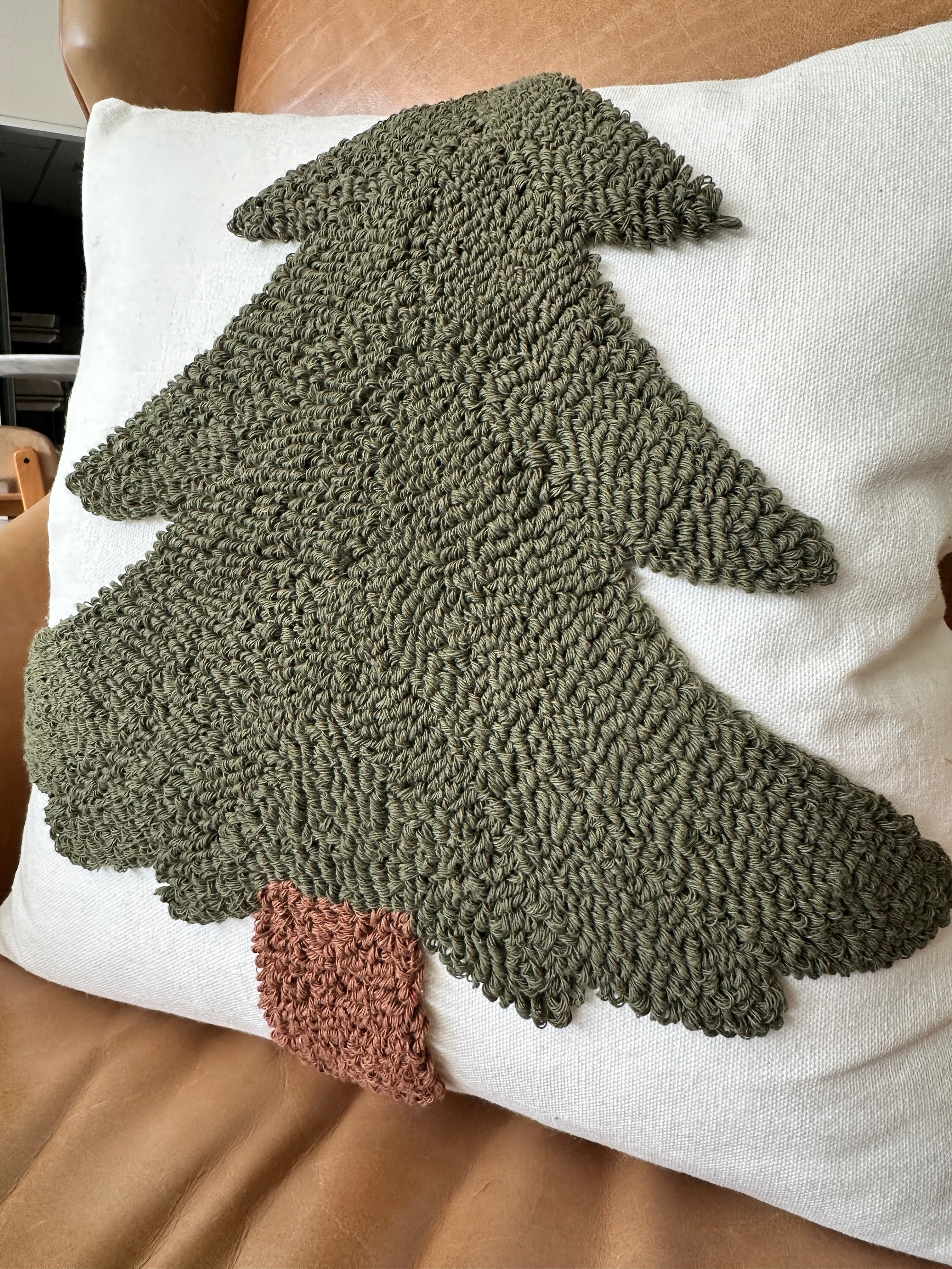 Decorative pillow with a textured green tree design on a white background