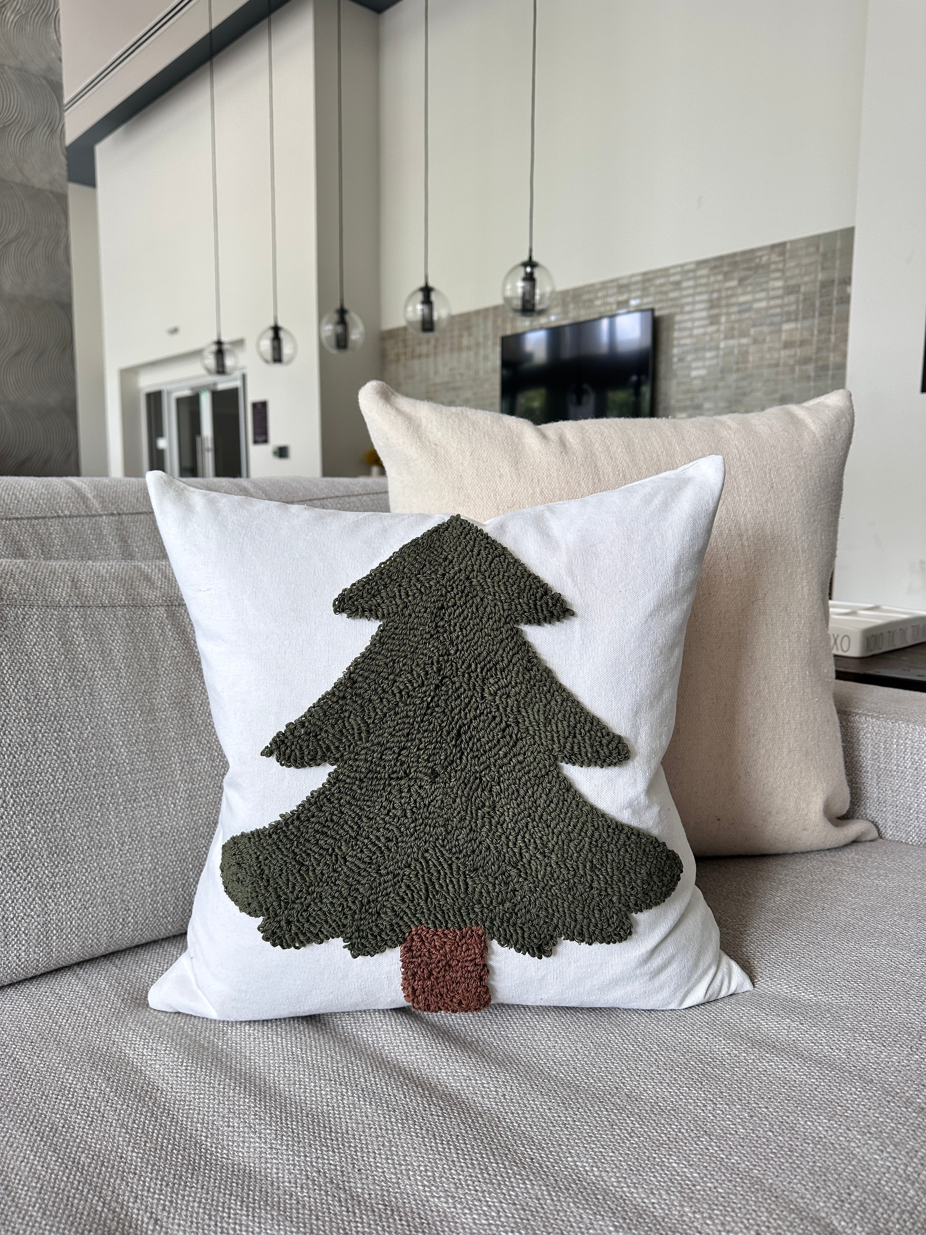 Decorative pillow with a tree design on a couch in a living room setting.