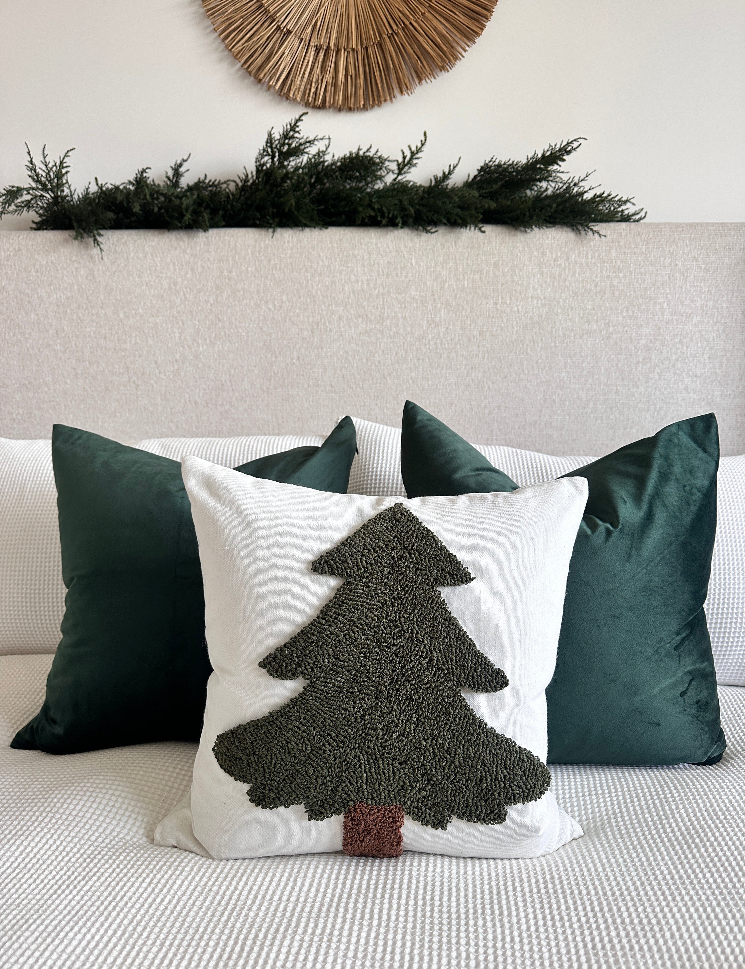 Decorative pillow with a tree design on a couch, surrounded by other pillows.
