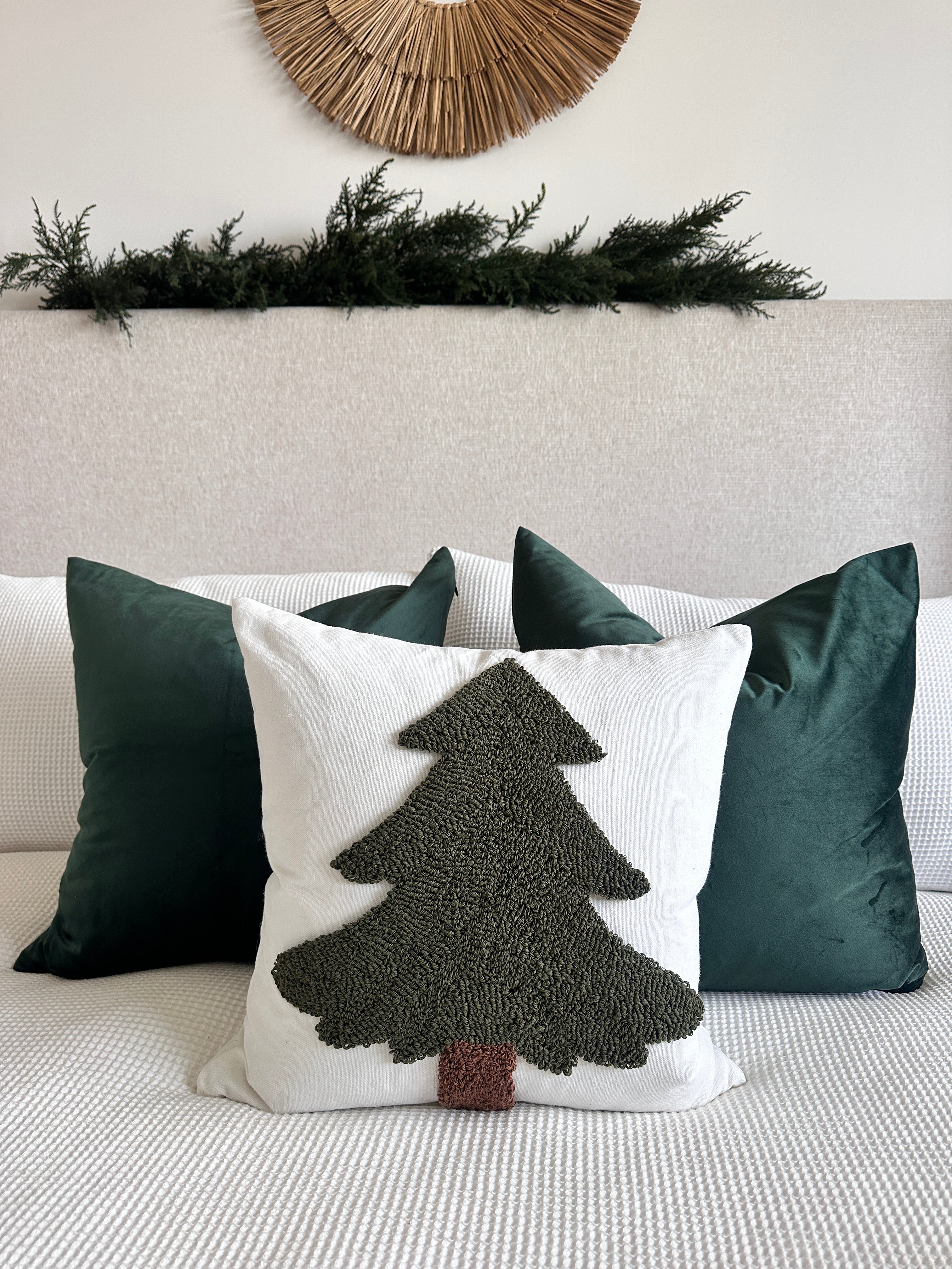 Decorative pillow with a tree design on a couch, surrounded by other pillows.