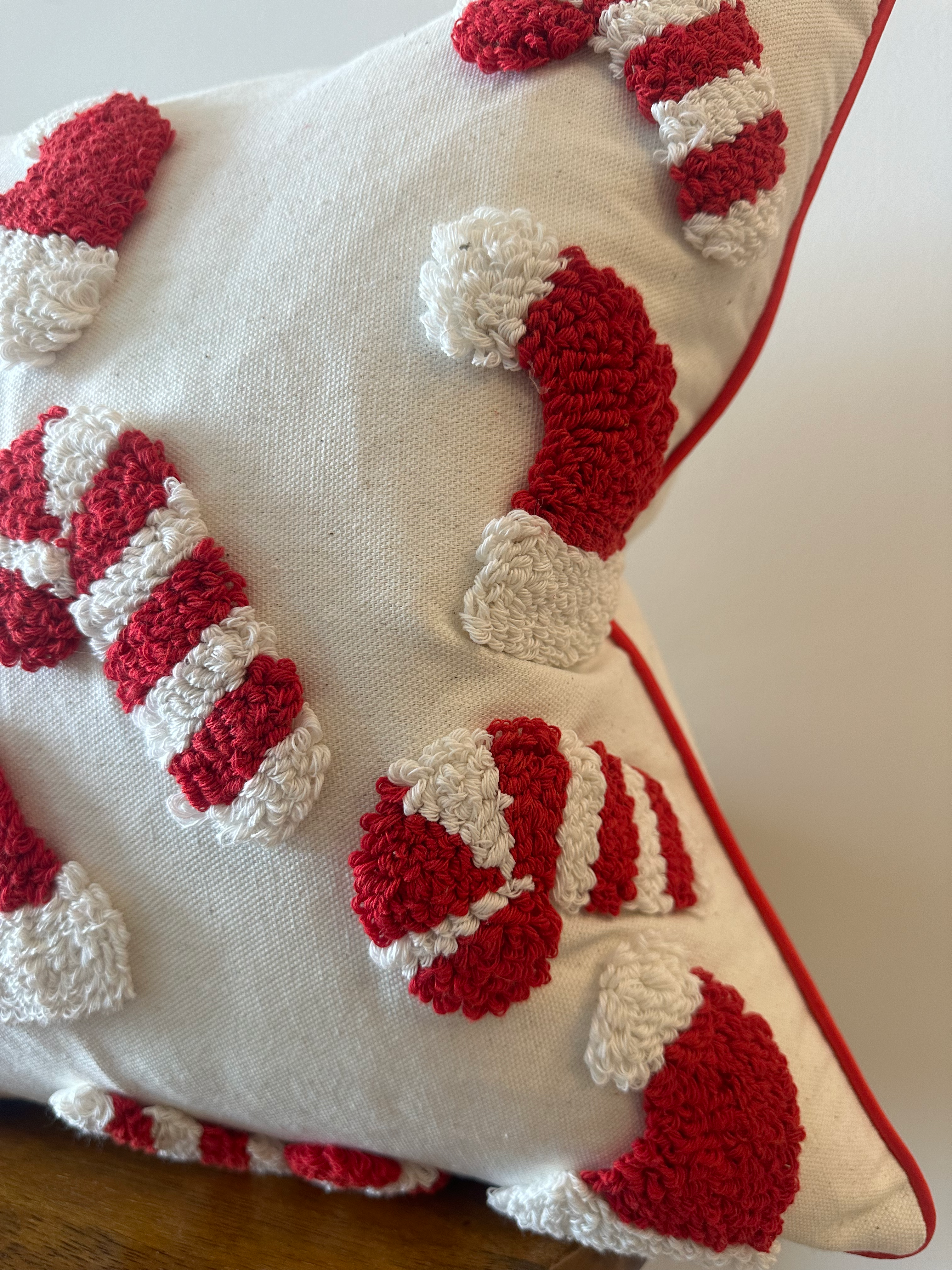 Decorative pillow with red and white candy cane pattern on a wooden surface.