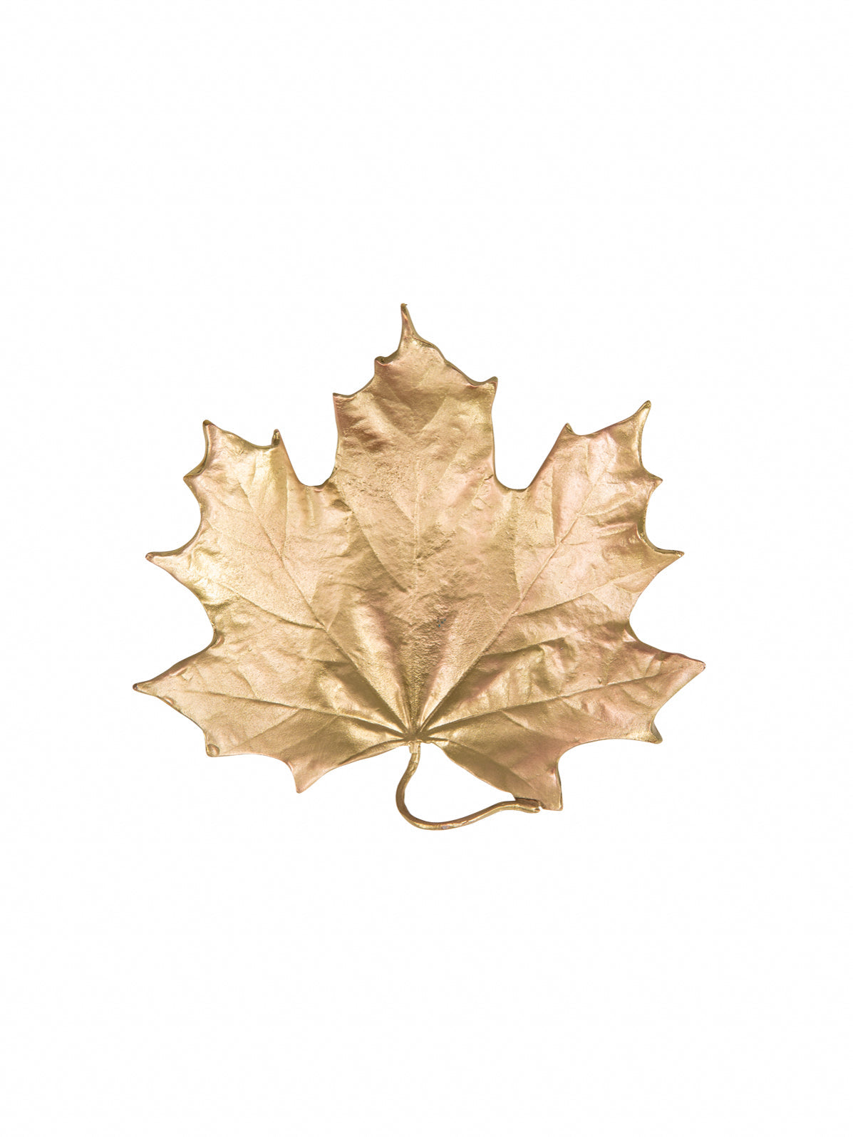A gold-colored forged metal dish shaped like an maple leaf against a white background.