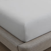 Gray fitted sheet on a bed with a wooden floor.