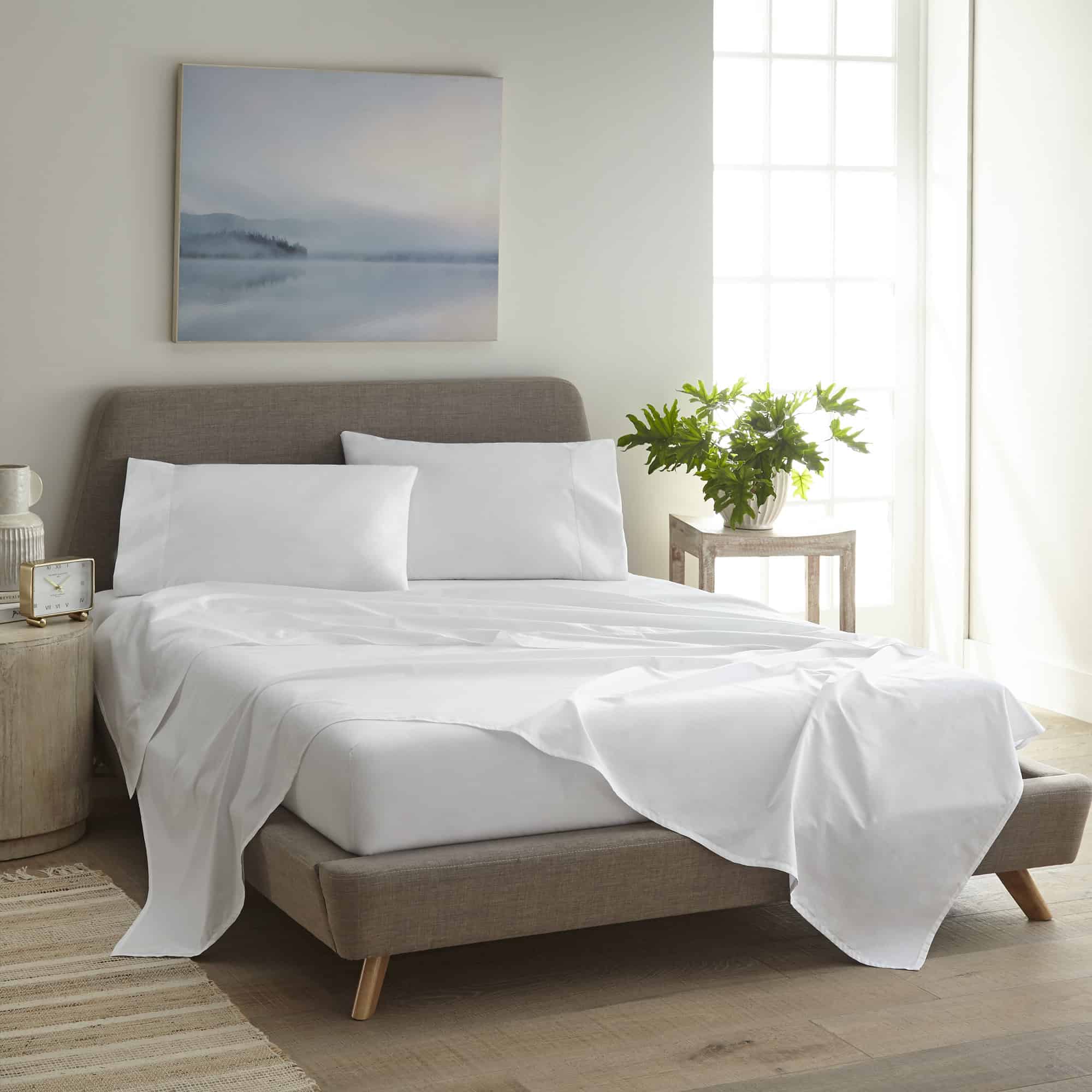 Neatly made bed with white bedding in a bright bedroom.