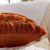 Brown textured pillow with pumpkin design on a white surface