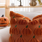 Decorative pillow with pumpkin pattern on a couch with a pumpkin decoration in the background.