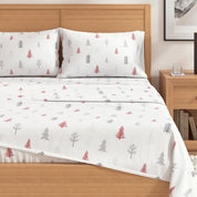 Bed with white bedding featuring red and green tree patterns, wooden headboard and nightstand.