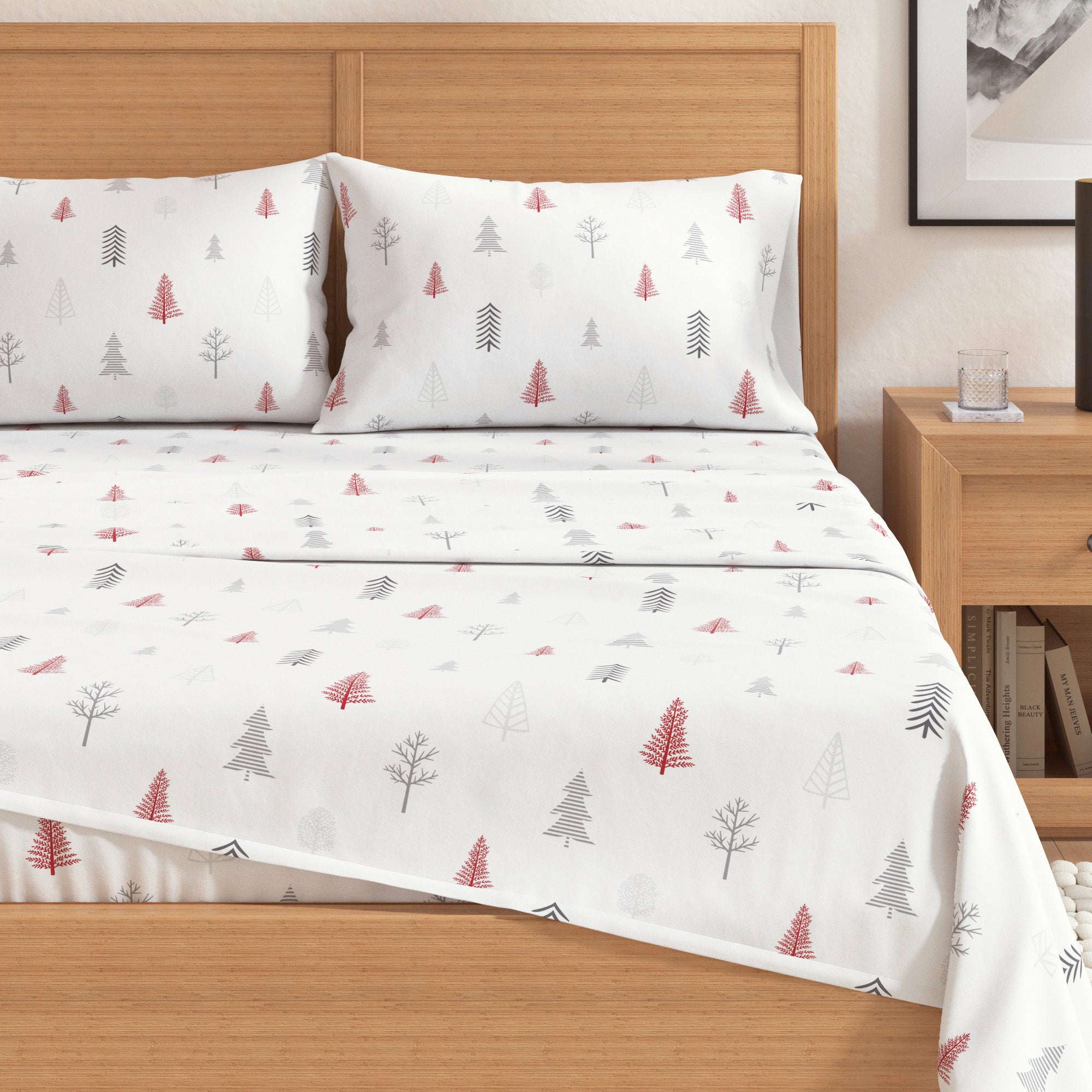 Bed with white bedding featuring red and green tree patterns, wooden headboard and nightstand.