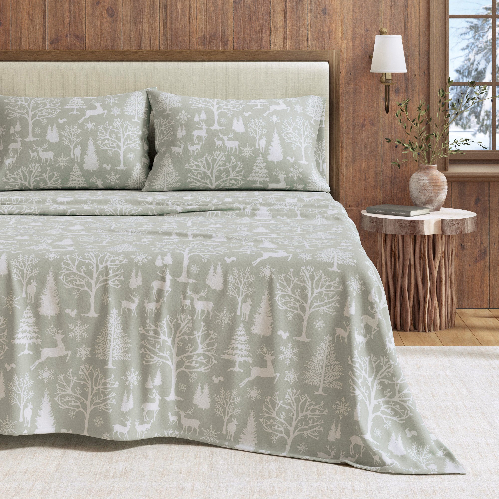 Bed with a forest patterned comforter in a bedroom setting.