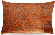 A brownish orange throw pillow with a traditional geometric pattern.