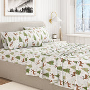 Bed with Christmas-themed bedding featuring deer and trees in a bedroom setting.