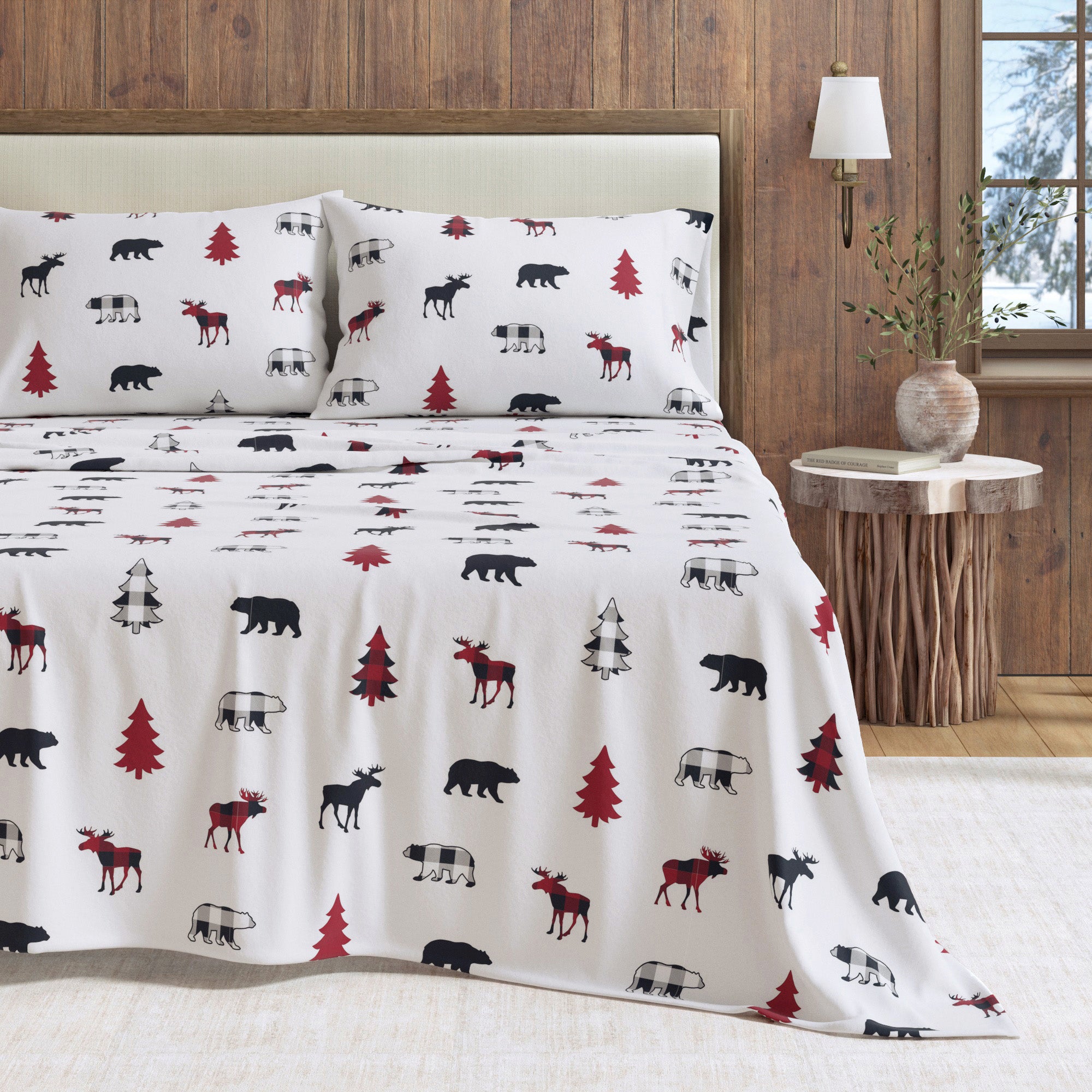 Bedding set with nature-themed design featuring moose, trees, and bears on a white background.
