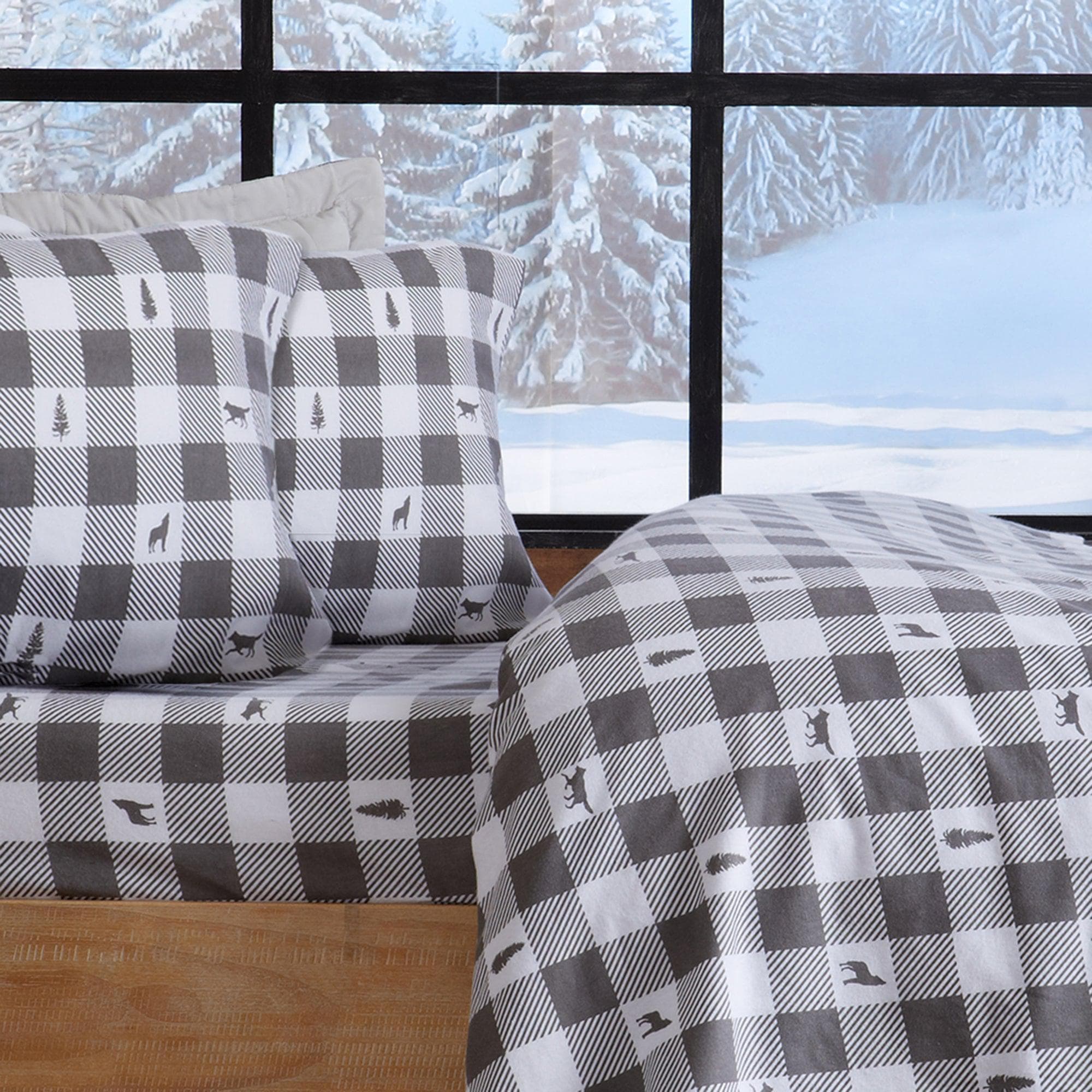 Plaid bedding set with animal patterns in a room with large windows showing a snowy landscape.