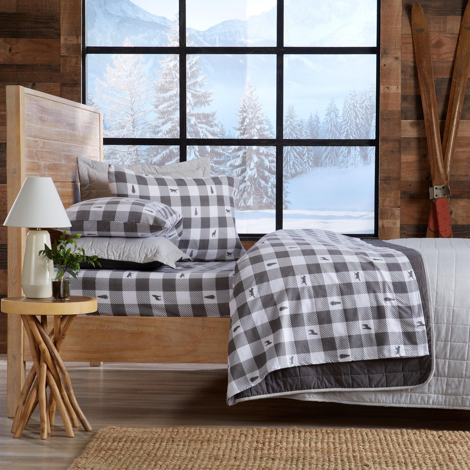Bedroom with checkered bedding and wooden headboard, large window showing snowy landscape.