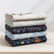 Stack of folded fabric with various patterns on a light surface.