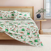 Dinosaur-themed bedspread on a bed in a bedroom setting
