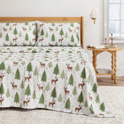 Christmas-themed bedspread with reindeer and trees on a bed in a bedroom setting.