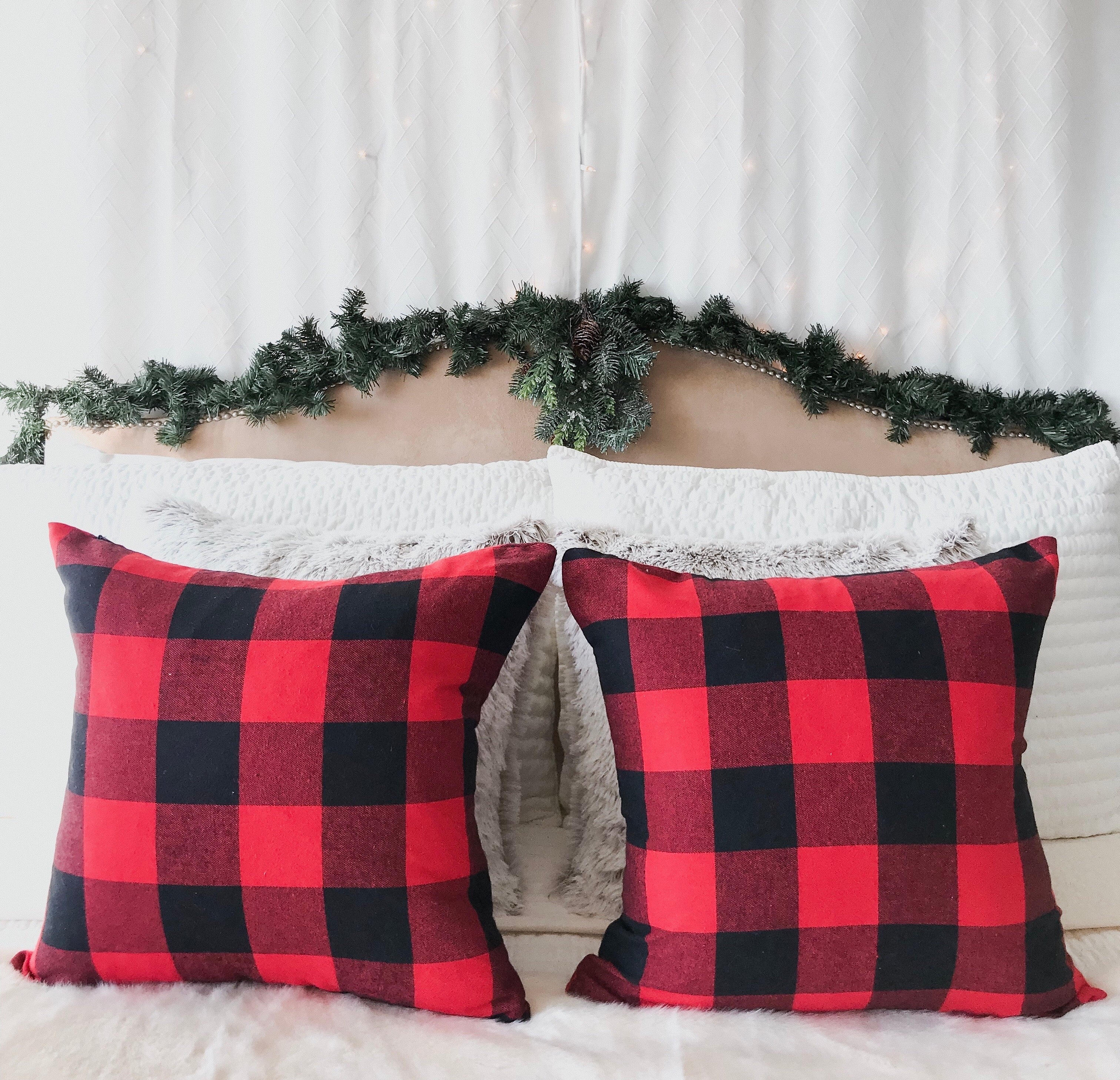 Red and black checkered pillows on a bed with a decorative headboard and garland.