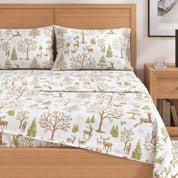 Bedding set with forest design on a bed in a bedroom setting.