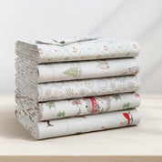 Stack of folded fabric sheets with animal pattern on a white surface