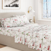 Bed with festive sheet set featuring Christmas-themed designs in a bedroom setting.
