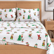 Christmas-themed bed sheet set with elves and trees on a wooden bed.