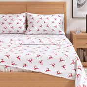 White bed sheets with red deer pattern on a wooden bed in a bedroom setting.