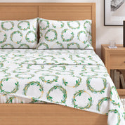 Bed with white sheets featuring green leaf patterns and matching pillowcases.