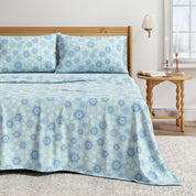 Blue floral patterned bedspread on a bed in a bedroom setting.