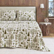 Bedding set with forest pattern on a bed in a room with wooden walls and a lamp.