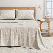 Bed with beige textured bedding and pillows in a bedroom setting.